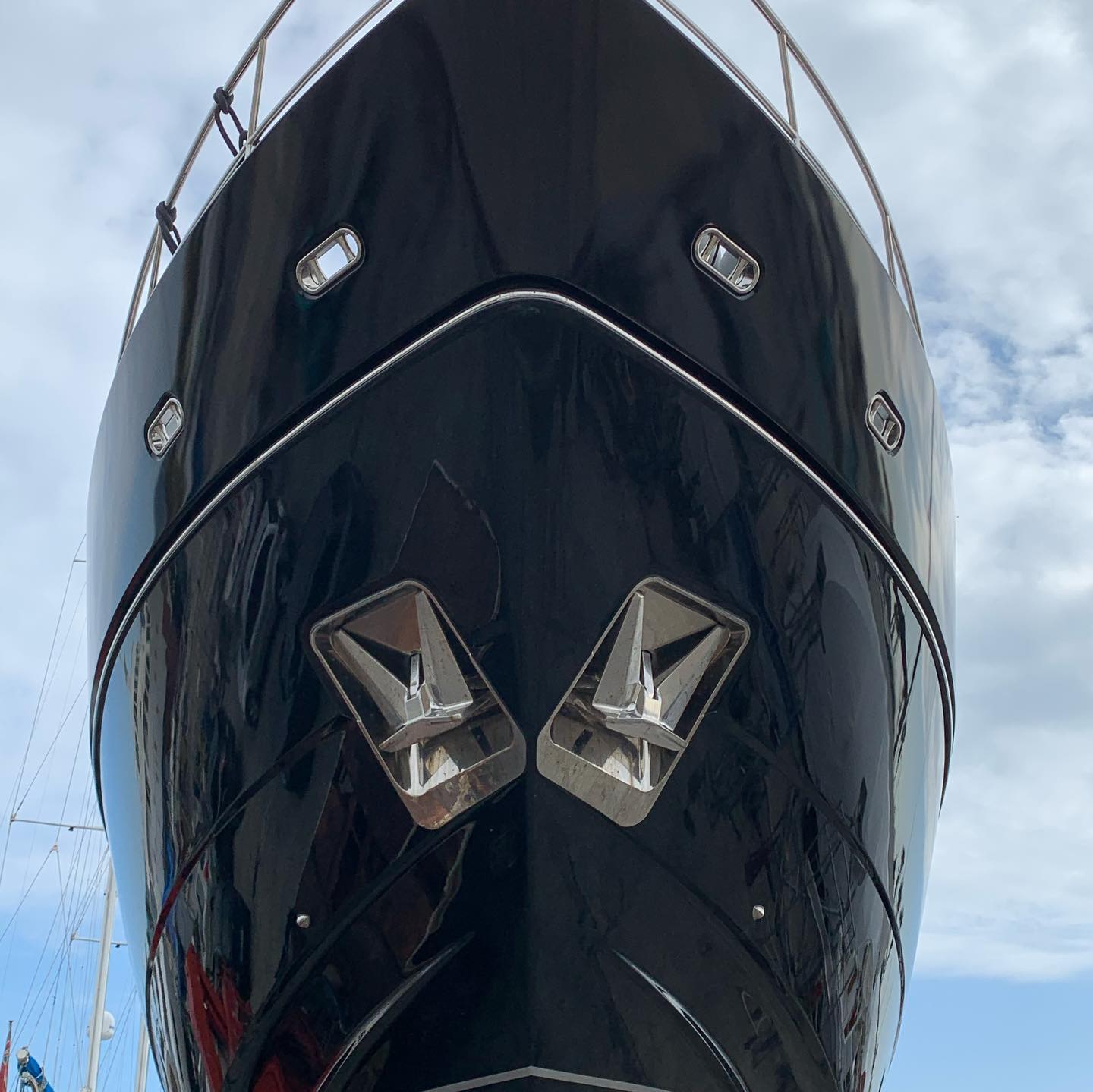 Bow of a yacht seen from below, its wrapped surface highly reflective.