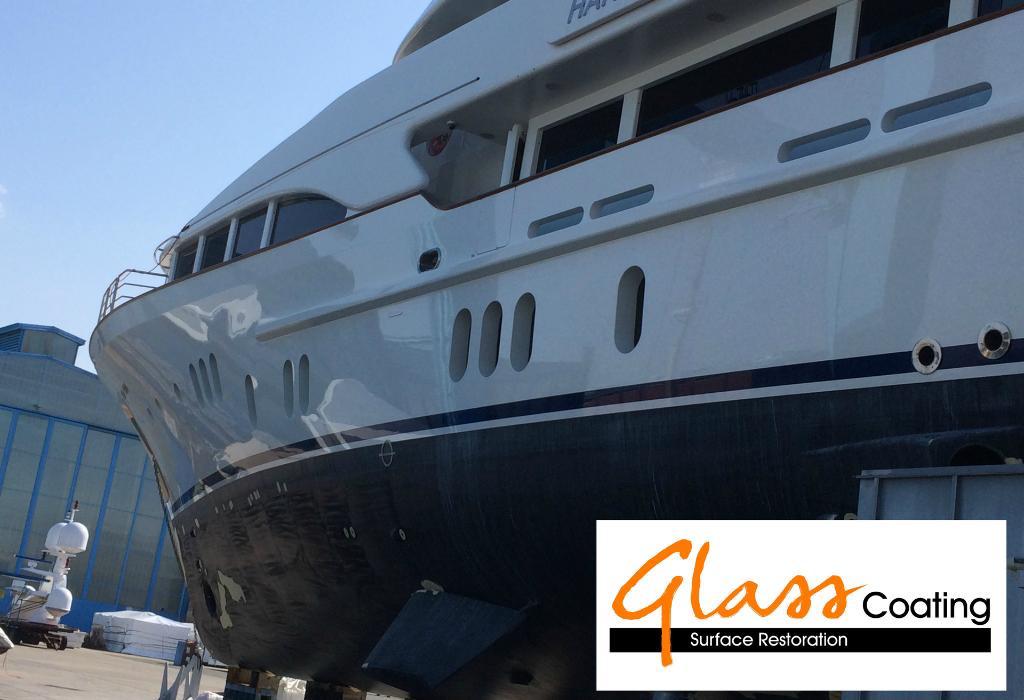 White yacht hull in a shipyard after glass coating surface restoration.