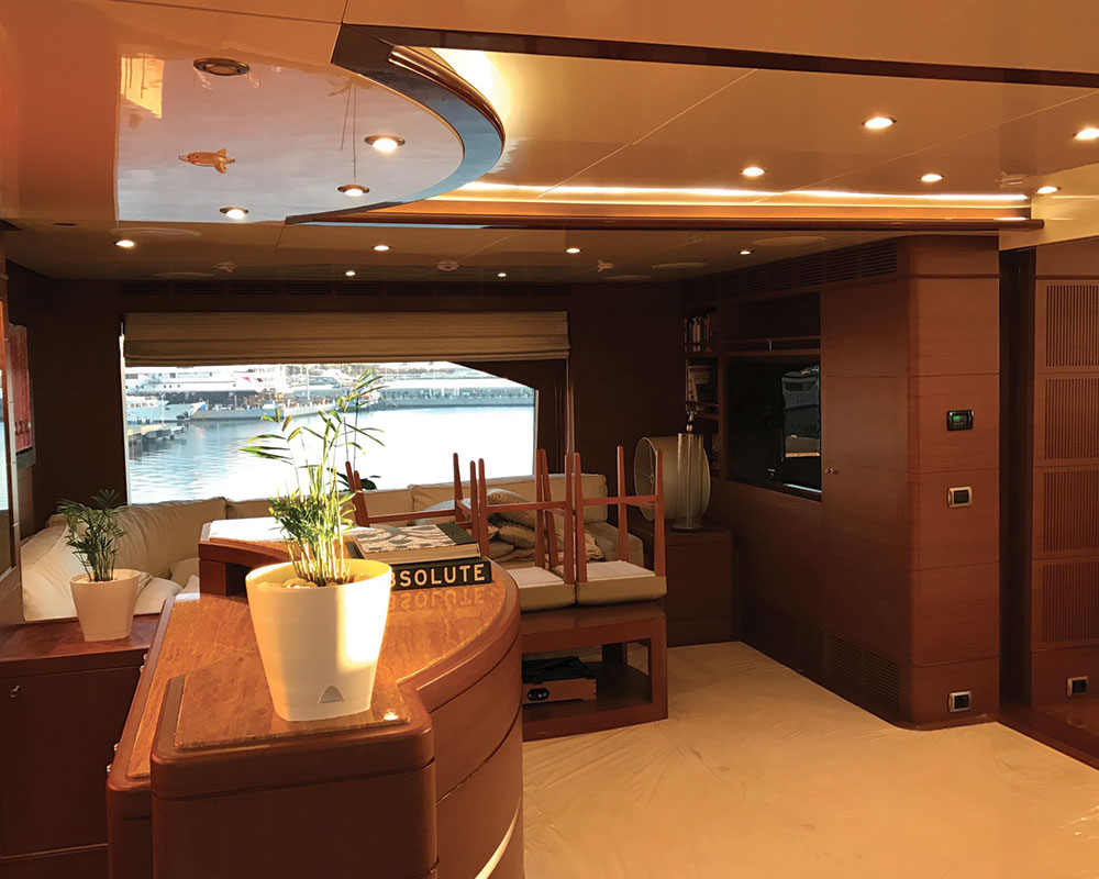 Wood-panelled yacht saloon with seating and a view over the marina.