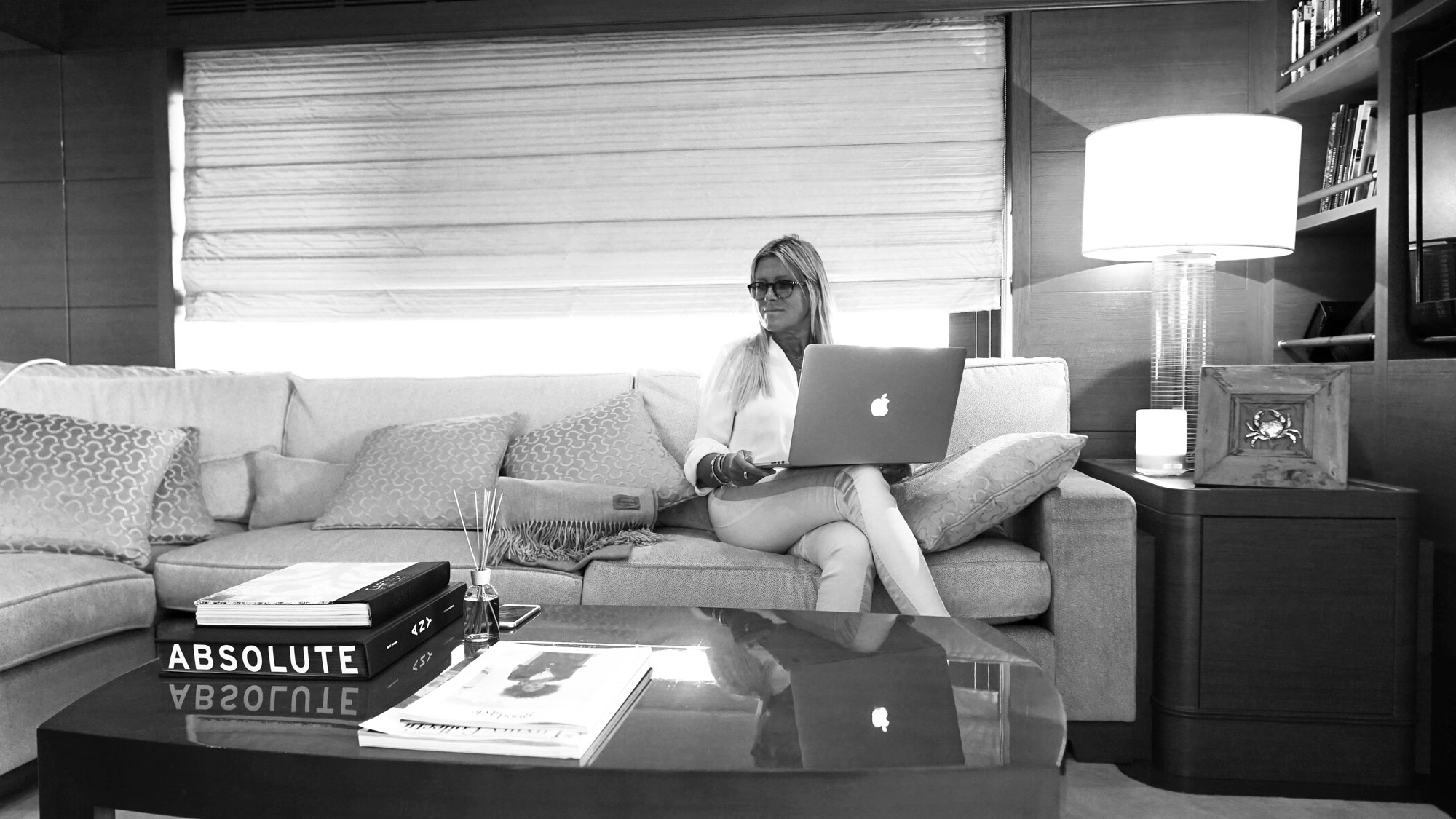 Cinzia Bulciolu working on a laptop on a sofa in a yacht interior.