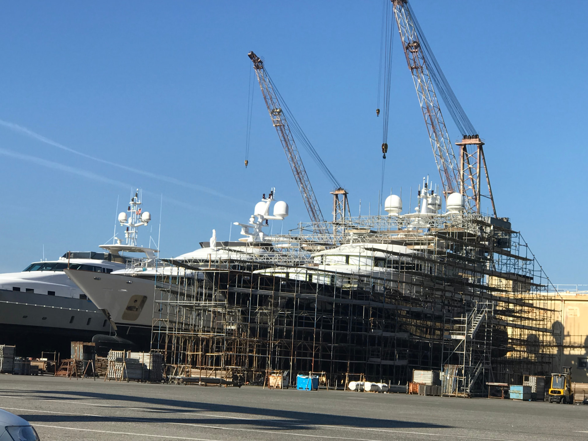 Large yachts in a Tuscan shipyard surrounded by scaffolding during refit works.
