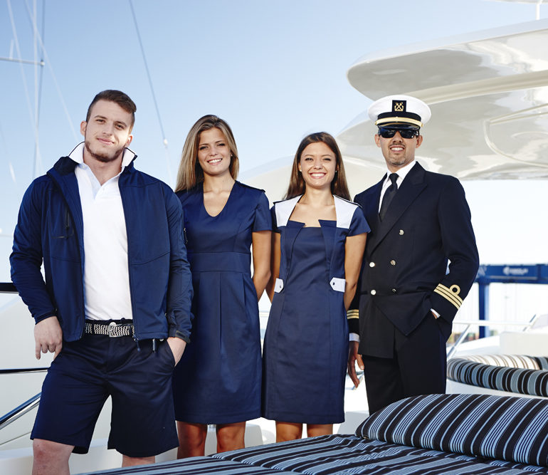Yacht crew in white uniform standing together on deck.